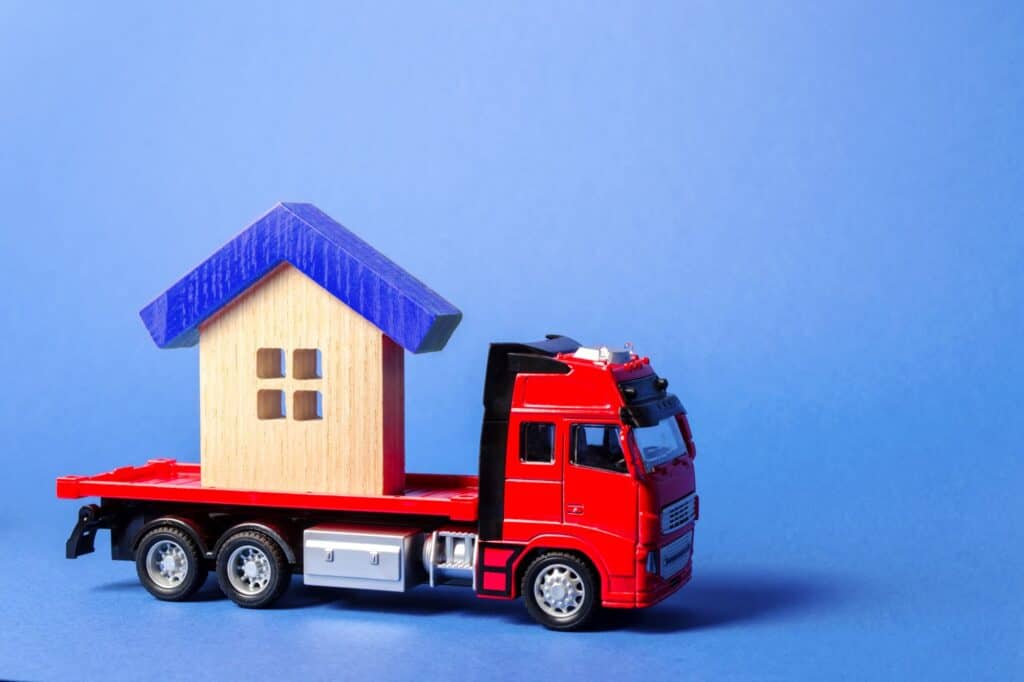 A blue-roofed house figurine at the back of the truck in the concept of house move