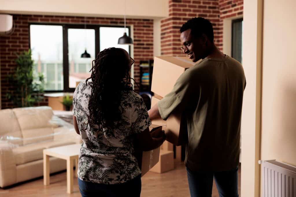 A couple carrying cardboard boxes to move in