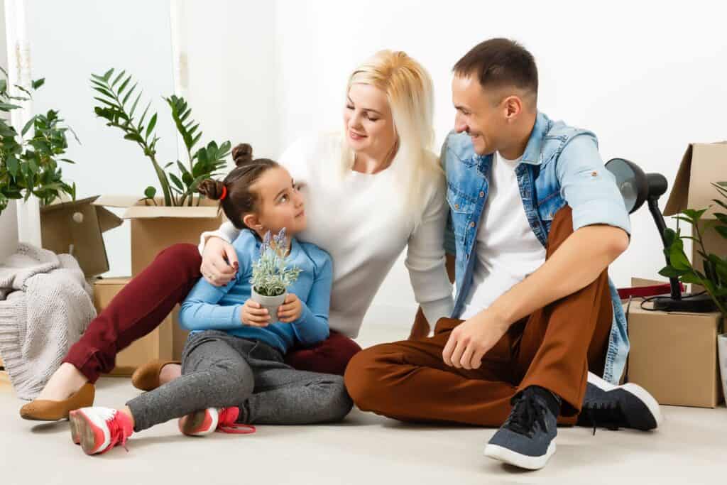 A happy family sitting on the wooden floor of their new place in the concept of house move