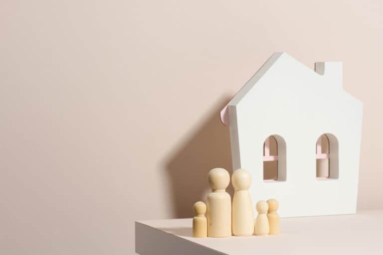 A wooden family and house figurine in the concept of moving to a new apartment