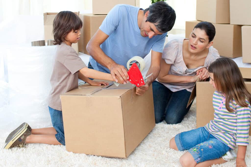 family packing items into cardboard boxes, preparing for a move