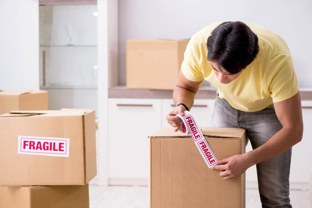 man labelling boxes as fragile using stickers