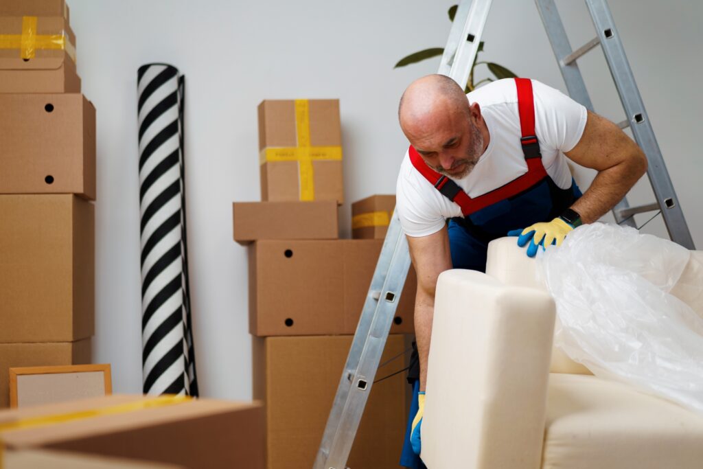 A mover in uniform packing the sofa in the concept of a good man and van in South London