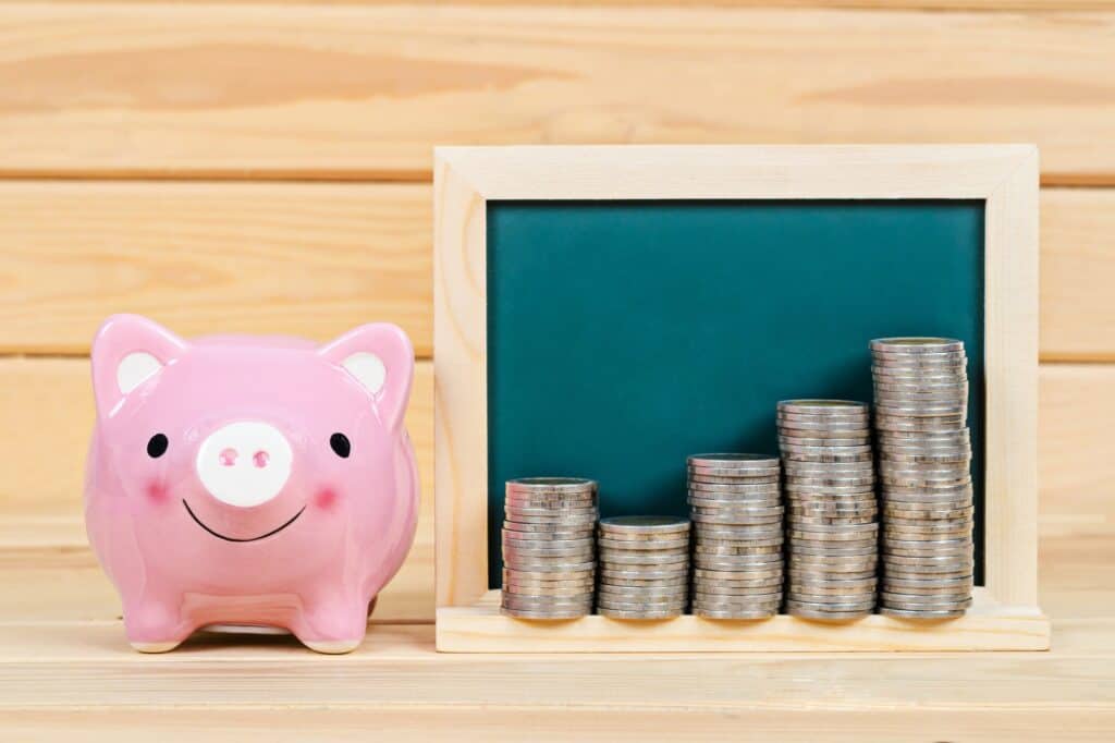 A piggy bank with coins beside it in the concept of saving money for the move to the South London area.