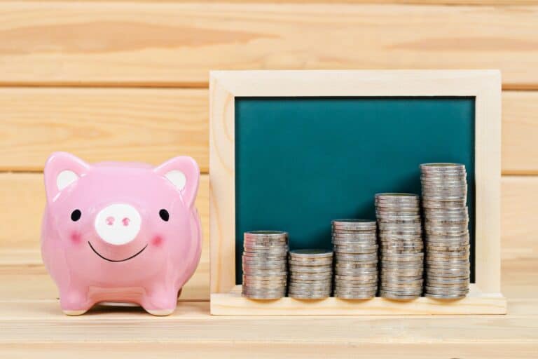 A piggy bank with coins beside it in the concept of saving money for the move to the South London area.