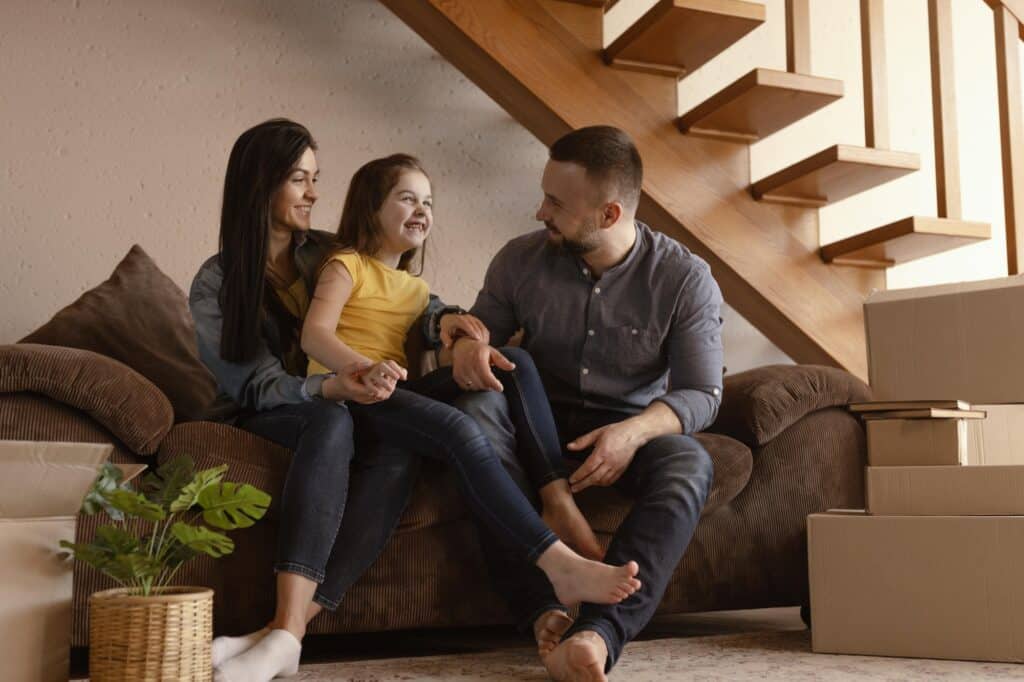 A happy family on the couch after moving house in the concept of 'How to Settle Into a New Home After Moving to South London'.