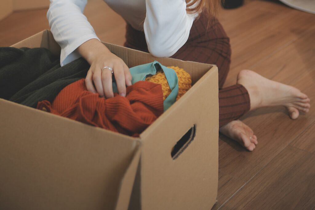 Cropped image of a woman unpacking clothes from the box upon moving in