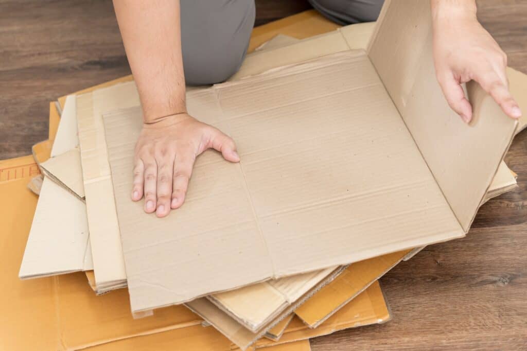 Cropped image of a man flattening used cardboard after the move